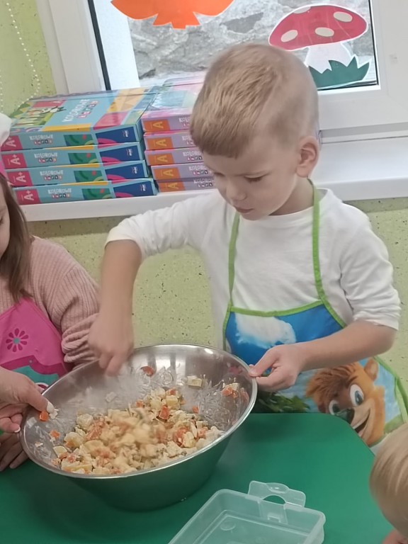 Chłopiec miesza łyżką sałatkę z pokrojonych warzyw