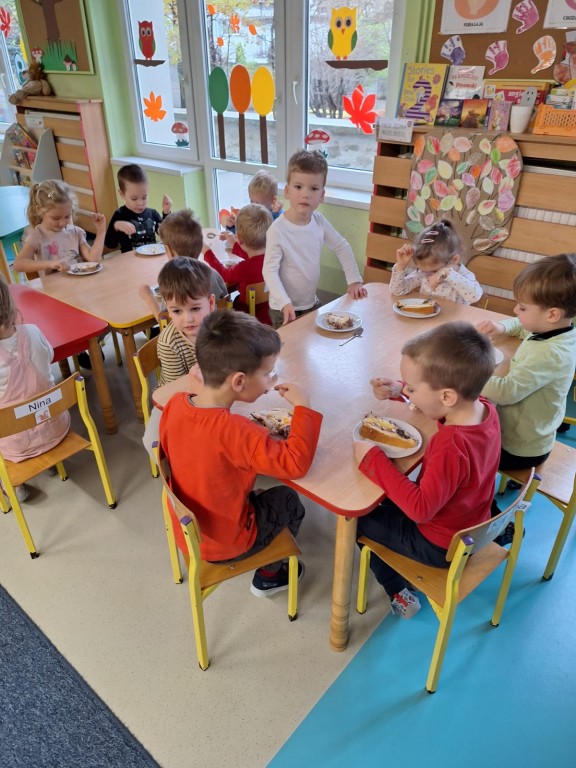 Dzieci siedzą przy stolikach i jedzą tort