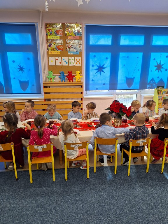 Dzieci siedzą przy stole w odświętnych strojach