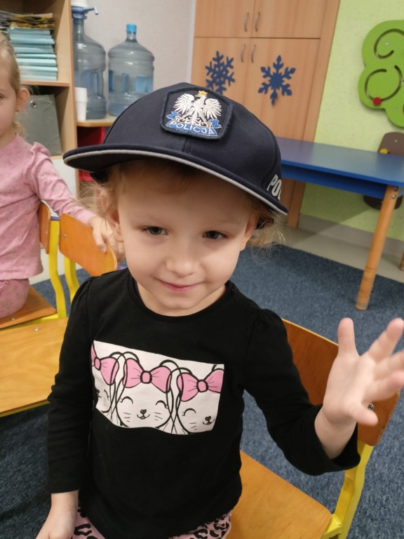 Dziewczynka pozuje w czapce policjanta