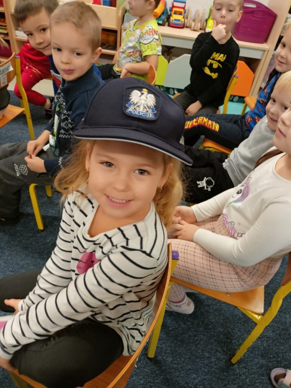 Dziewczynka pozuje do zdjęcia w czapce policjanta