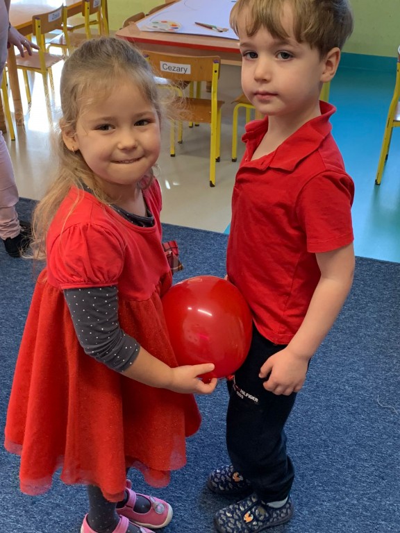 Dziewczynka i chłopiec tańczą razem z balonem 