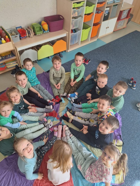 Dzieci siedzą na podłodze i w kolorowych skarpetkach pozują do zdjęcia