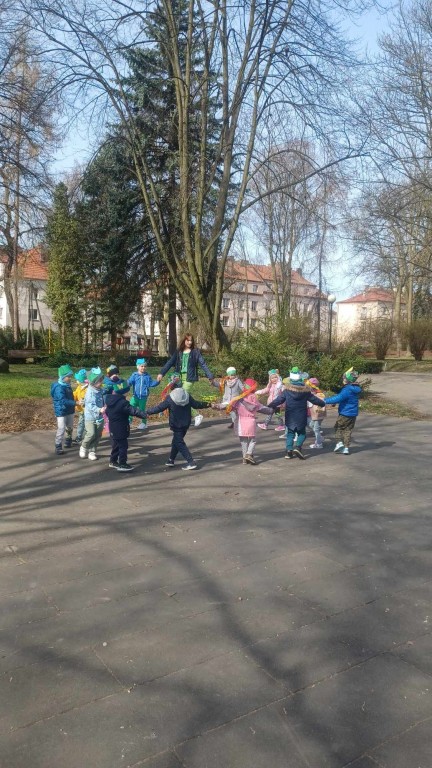 Dzieci z nauczycielką tworzą koło trzymając się za ręce