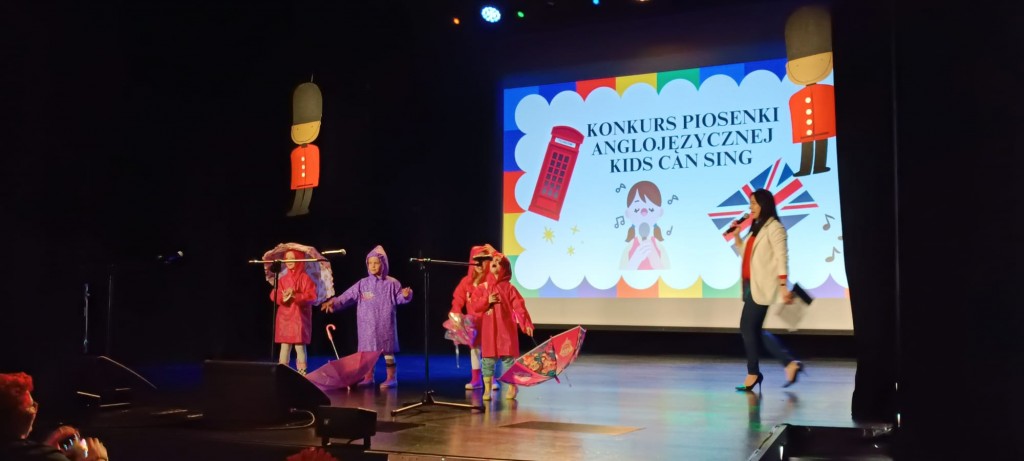 dzieci z parasolkami tancza i spiewaja na scenie