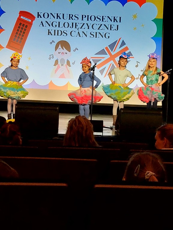 dziewczynki w kolorowych spodnicach tancza i spiewaja do angielskiej piosenki
