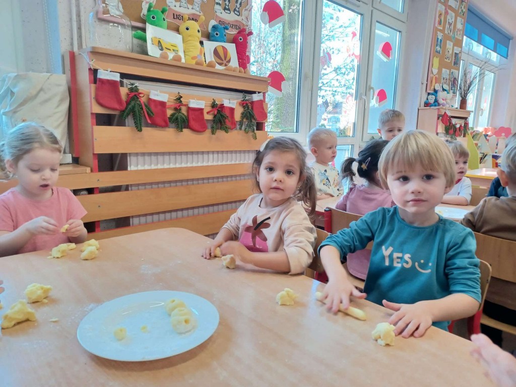 dzieci siedzą przy stoiku przygotowują się do kulania