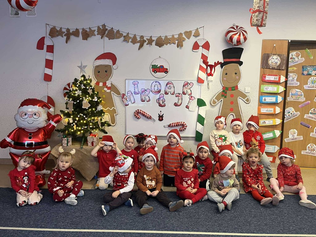 grupowe zdjęcie dzieci na tle mikołajkowej dekoracji w sali