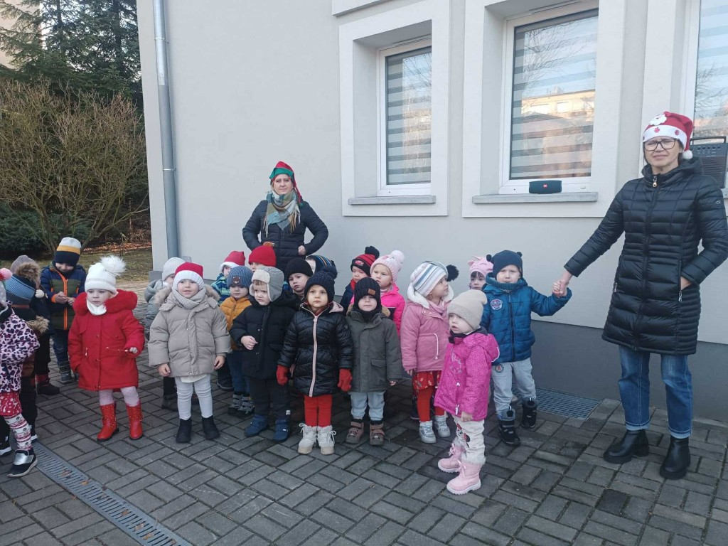 dzieci ubrane w zimową odzież wyczekują na podwórku nadejścia Mikołaja