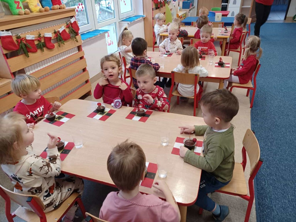 dzieci przy stoliku konsumują mikołajkowe babeczki
