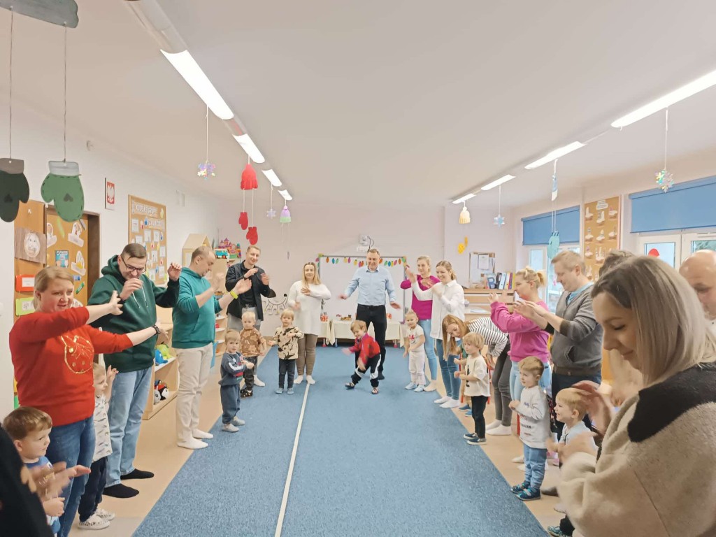 dzieci i rodzice stoją w kole naśladują ruchy do piosenki