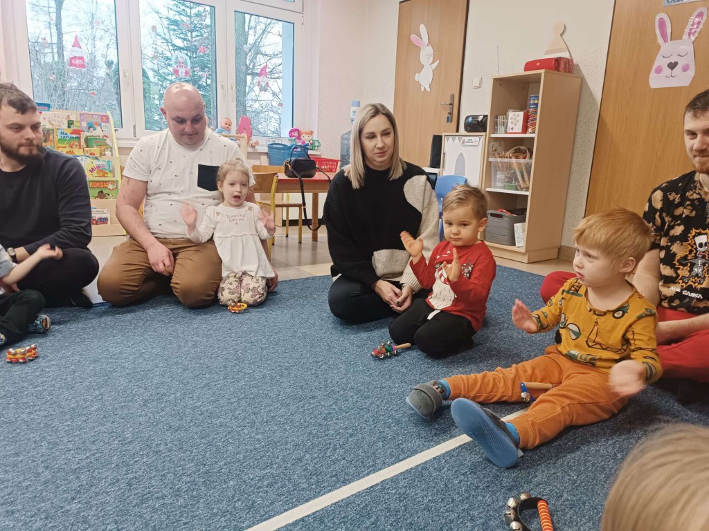 osoby siedzą w kole rytmicznie uderzają w ręce