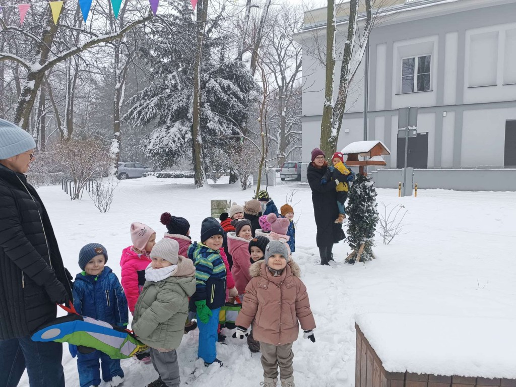 dzieci dokarmiają ptaki w karmniku