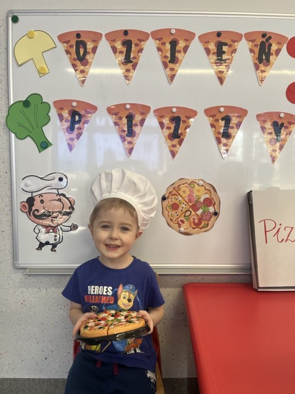 Chłopiec pozuze do zdjęcia na tle napisu Dzień pizzy