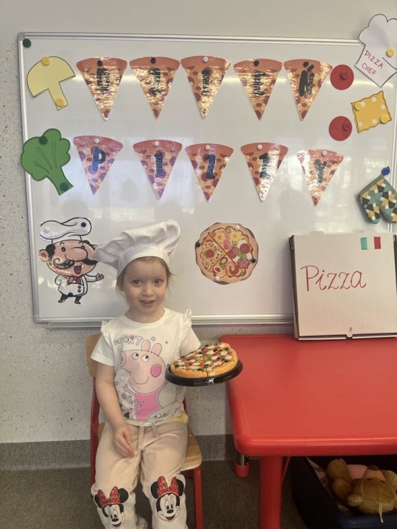 Dziecko pozuje na tle ścianki Dnia Pizzy