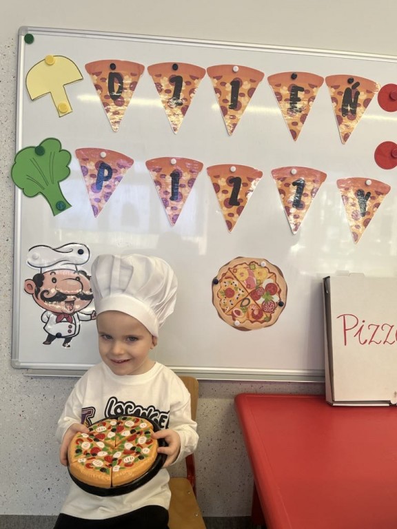 Chłopiec w czapce kucharskiej prezentuje pizze