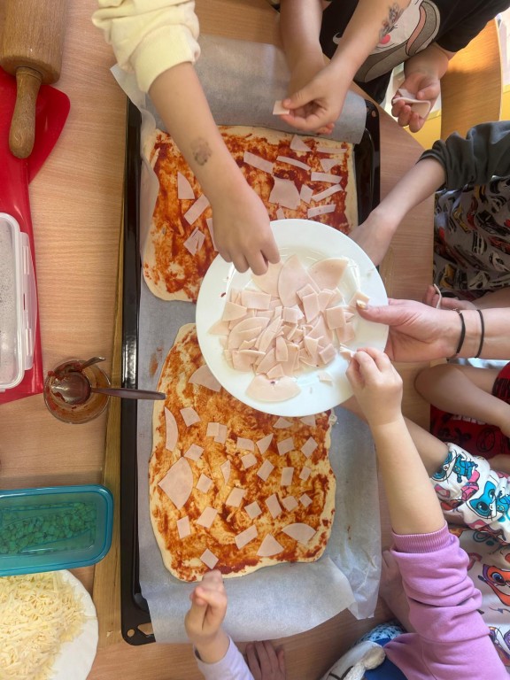 Dzieci układają szynkę na pizzę