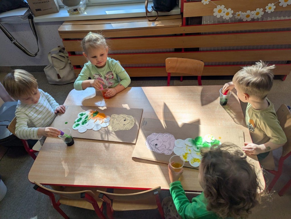 grupa dzieci pipetkami malują suknię Pani wiosny
