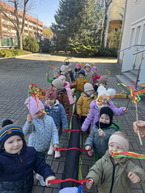 dzieci wyruszają na przemarsz z kolorowymi maikami