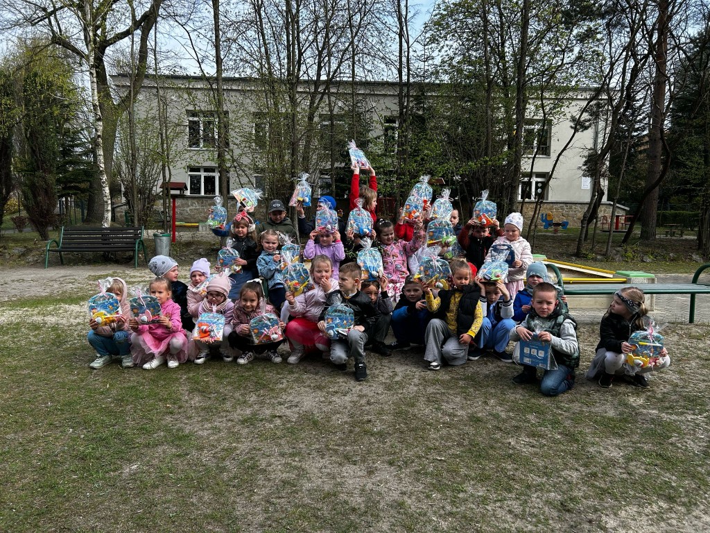 Dzieci na podworku trzymają w rękach prezenty