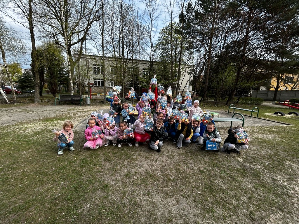 Dzieci na podworku trzymają w rękach prezenty