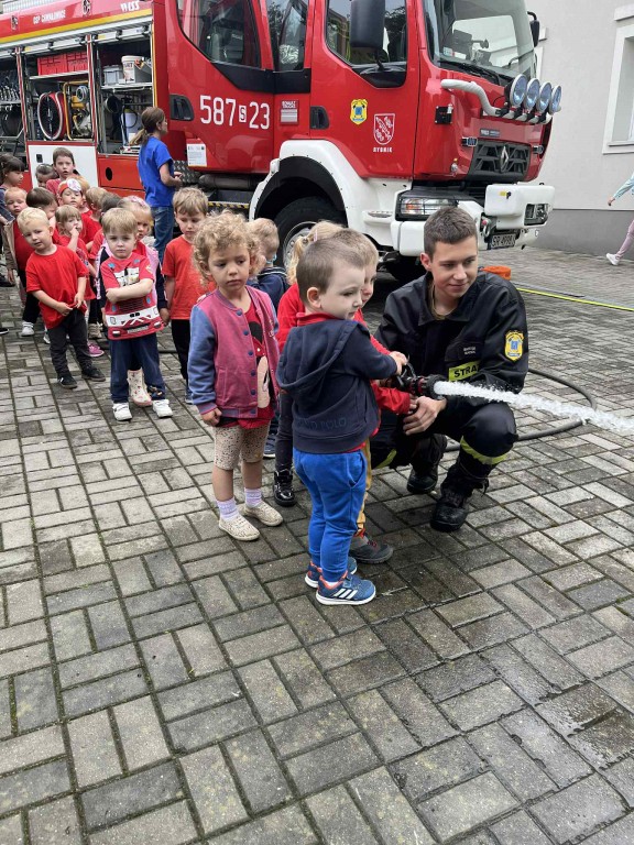 Dzieci leją wodę z prawdziwego węża strażackiego