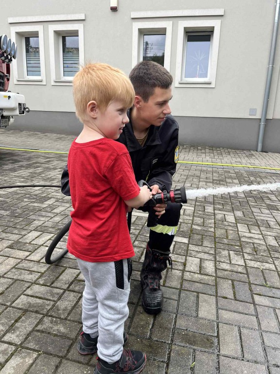 Dzieci leją wodę z prawdziwego węża strażackiego