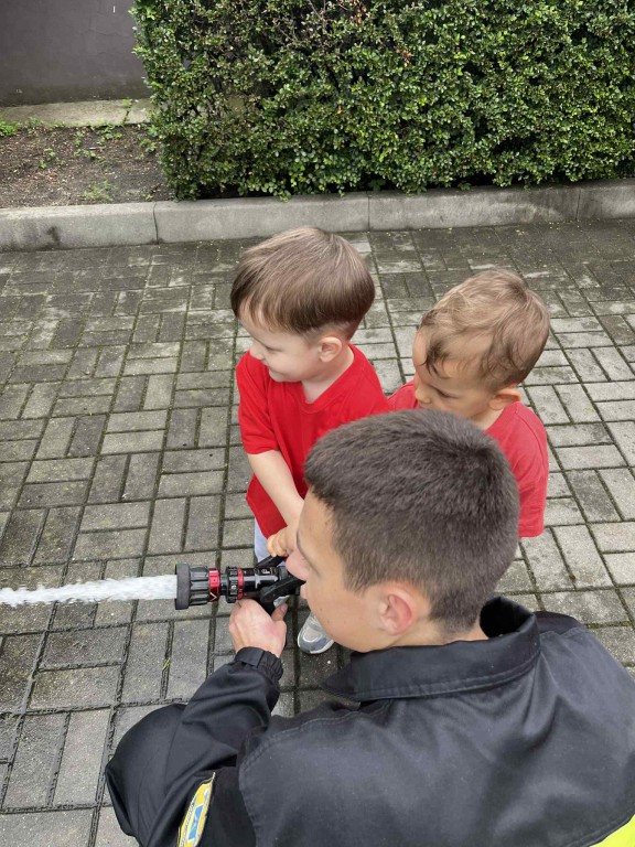 Dzieci leją wodę z prawdziwego węża strażackiego