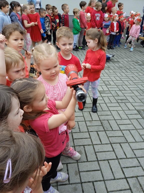dzieci trzymaja sprzety od wozu strazackiego
