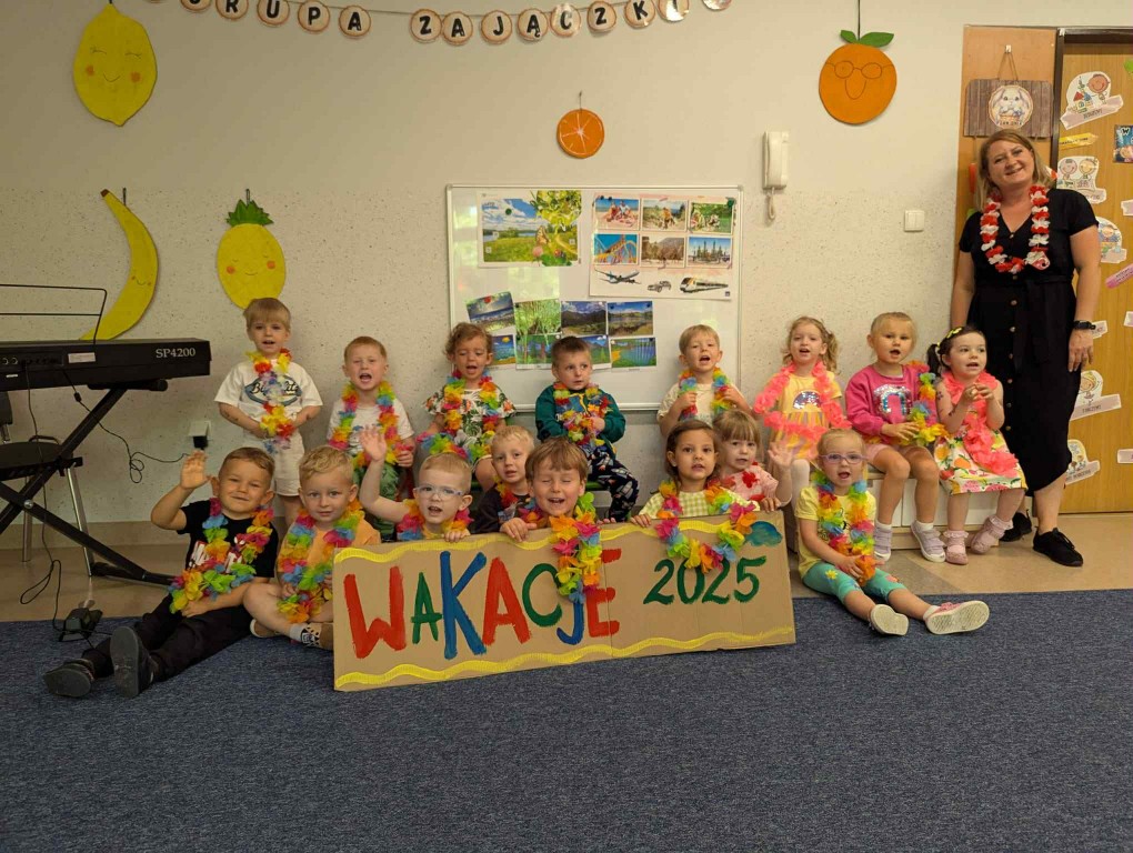 Zdjęcie grupowe maluchów z tablicą Wakacje 2025
