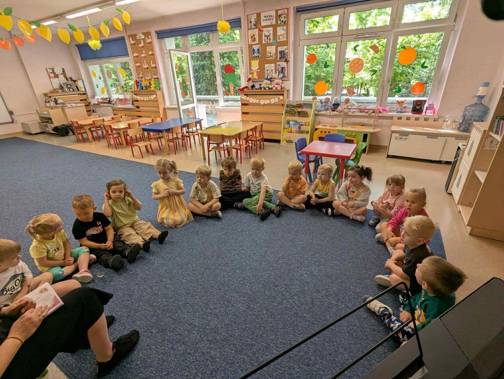 Dzieci siedzą w kółeczku na dywanie