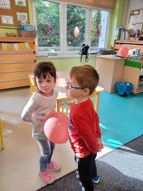 dziewczynka i chłopiec wspólnie starają się utrzymać balon między sobą