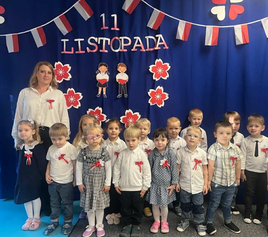 Zdjęcie grupowe na tle dekoracji z okazji 11 listopada w odświętnych strojach