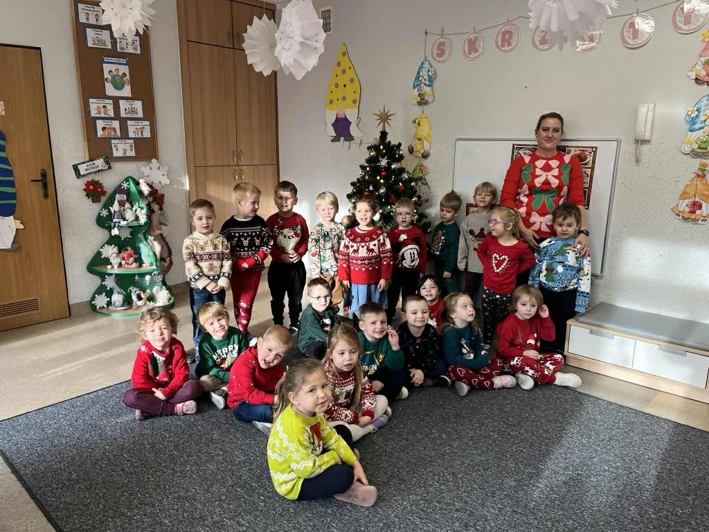 Zdjęcie grupowe dzieci z wychowaczynią w świątecznych sweterkach