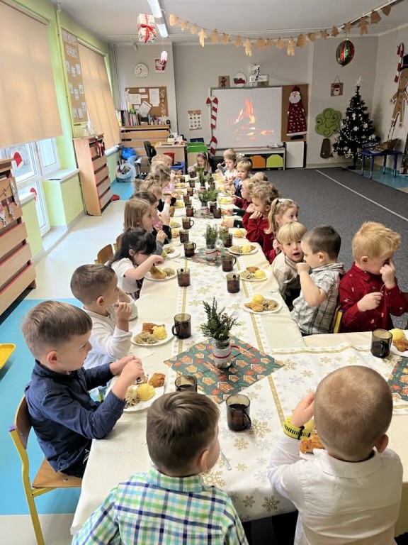 Dzieci siedzą przy wspólnym wigilijnym stole