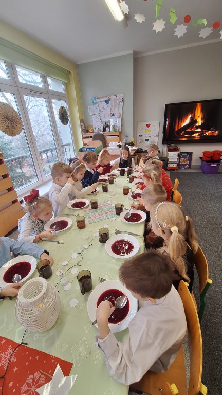Dzieci siedzą przy stole wigilijnym 