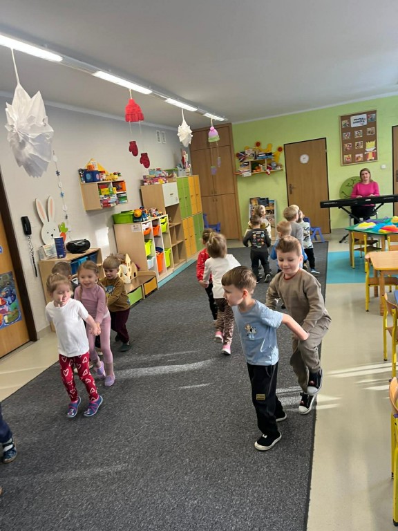 dzieci ciągną się za rączki w parach naśladując jazdę na saneczkach