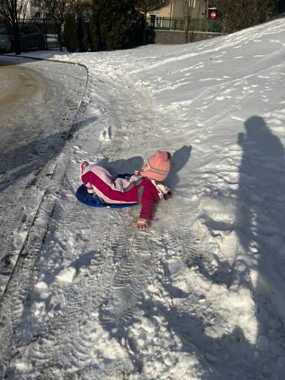 dziewczynka zjeźdża na talerzyku z górki