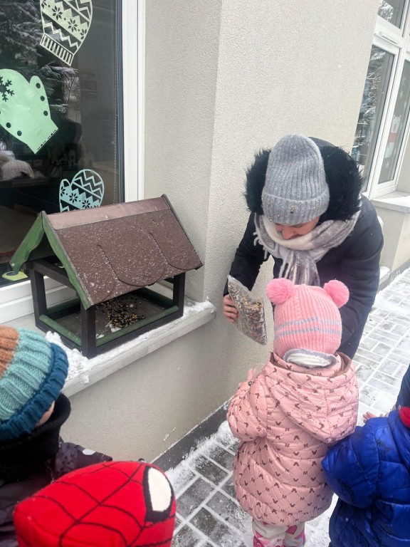 Wychowawca sypie ziarna dla ptaków na rączki dzieci