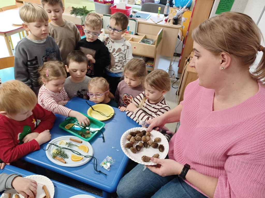 dzieci układają materiał przyrodniczy na talerzykach tworząc obraz symetryczny
