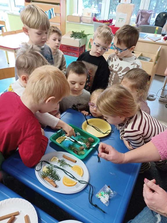 dzieci układają materiał przyrodniczy na talerzykach tworząc obraz symetryczny