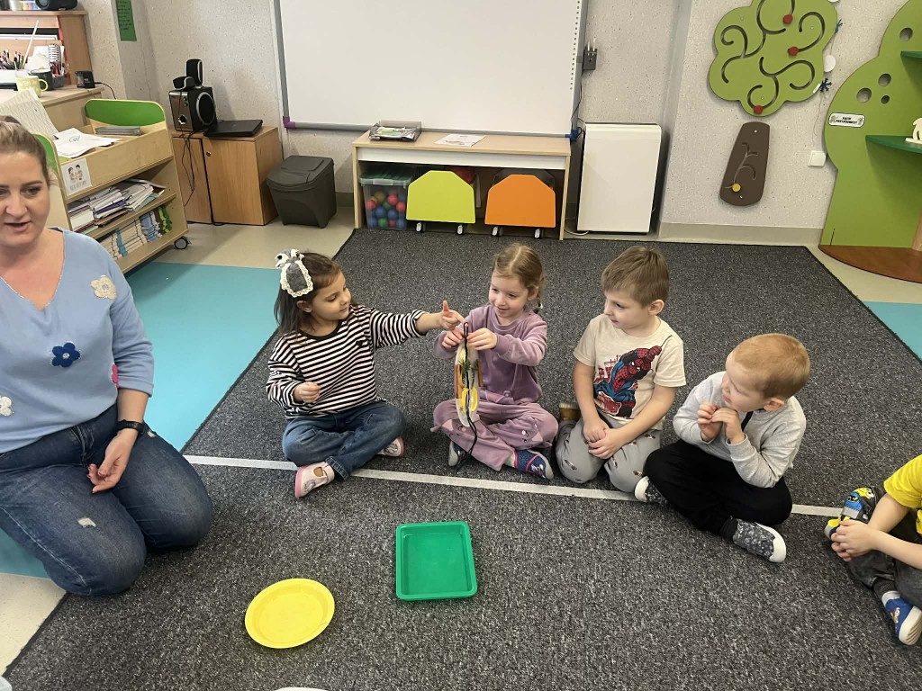 dzieci podają sobie witraże i przyglądają się im