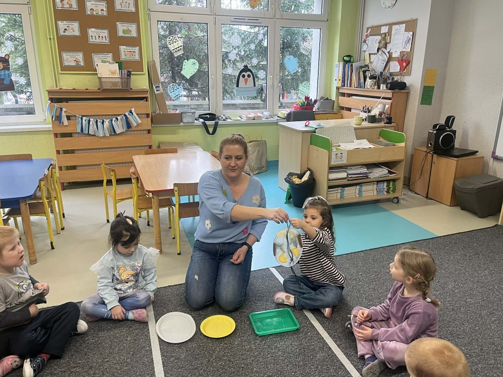 dzieci podają sobie witraże i przyglądają się im