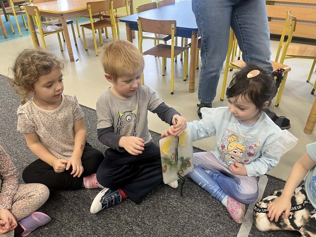 dzieci podają sobie witraże i przyglądają się im