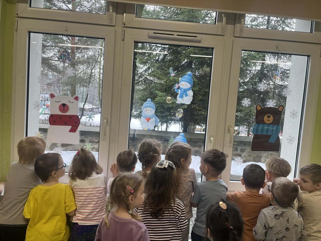 dzieci podziwiają witraże przez okno w sali zabaw