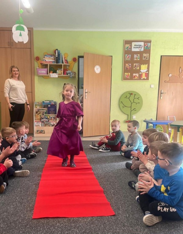 Dziewczynka  w balowej sukience przechodzi się po czerwonym dywanie