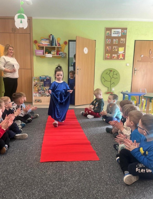 Dziewczynka  w balowej sukience przechodzi się po czerwonym dywanie