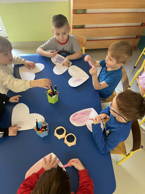 chłopcy przy stoliku ozdabiają serduszka dla dziewczynek