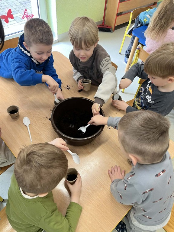 Dzieci ładują ziemię do doniczki