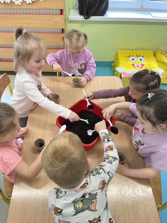 Dzieci nabierają ziemię łyżką